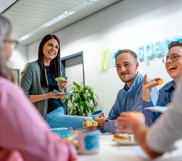 Fünf Personen sitzen gemütlich um einen Tisch und essen Kuchen.